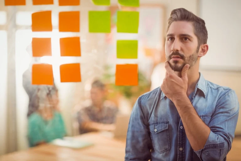 Homme réfléchissant devant des notes adhésives représentant une stratégie de prospection téléphonique.