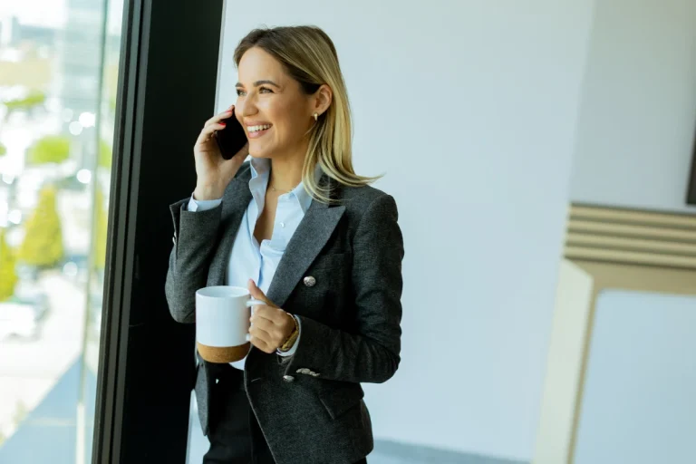 Businesswoman prenant un café tout en passant un appel personnalisé dans le cadre d’une stratégie de prospection B2B