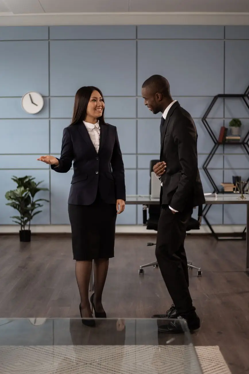 Deux professionnels échangent debout dans un bureau, illustrant la relation entre un client et son prestataire de prospection
